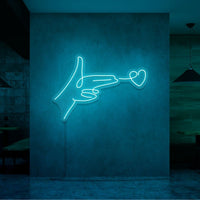 Neonlamp van een hand pistool met hartje als kogel in kleur cyaan