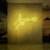 Neonlamp van een hand pistool met hartje als kogel in kleur geel