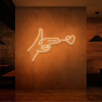 Neonlamp van een hand pistool met hartje als kogel in kleur oranje