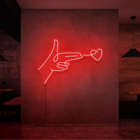 Neonlamp van een hand pistool met hartje als kogel in kleur rood