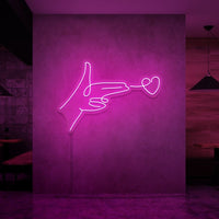 Neonlamp van een hand pistool met hartje als kogel in kleur roze